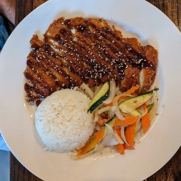 Crispy chicken katsu with teriyaki sauce, sesame seeds, white rice, and stir-fried vegetables.